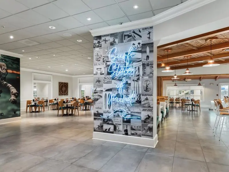 Lobby with a tall art wall of photographs and dining tables beyond.