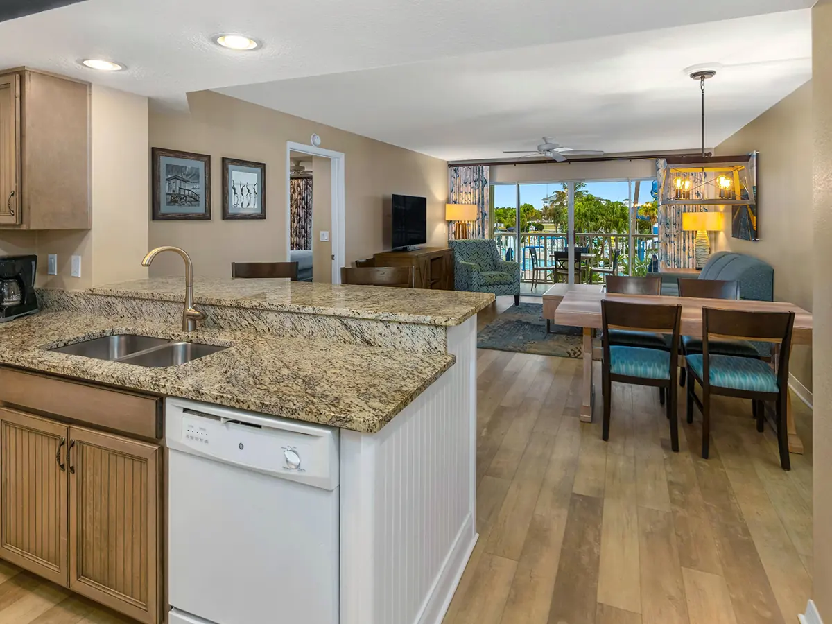 Similar room (illustrative): open kitchen with granite counter and sink, wooden cabinets and a dining table with a view toward a balcony.