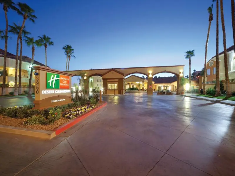 Resort entrance road at dusk with palm trees and a Holiday Inn Club Vacations sign.