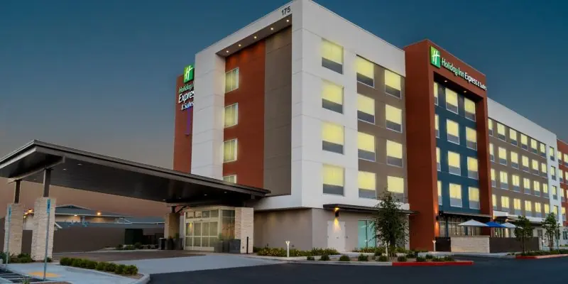 Hotel building at dusk with a Holiday Inn Express sign, lit windows and a covered entrance.