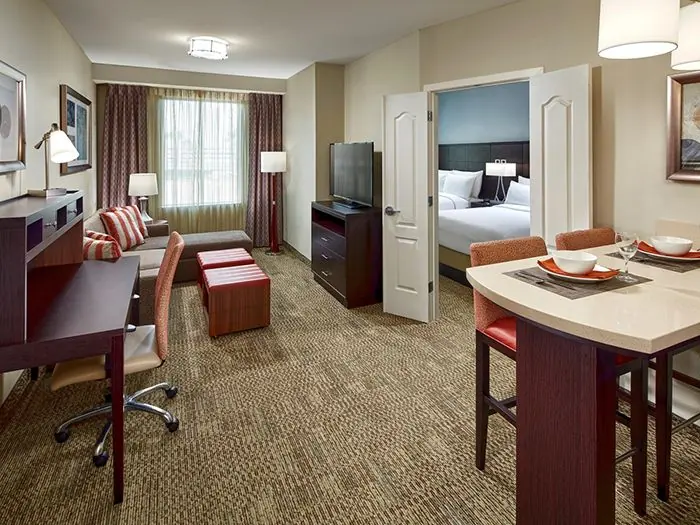 Living/dining area with desk and door to bedroom.