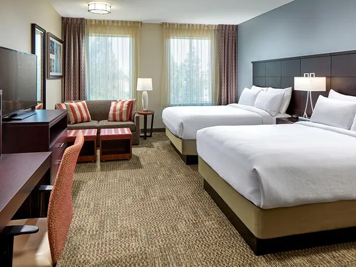 Two queen beds with sofa and desk.